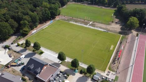 Luftbild Sportanlage Am Vennberg mit zwei Rasenplätzen udn dichtem Baumbewuchs am rechten und linken Rand, rechts Teil der Tartanbahn, unten links Ausschnitt vom Skatepark Gebäude, Autos und vereinzelt Bäume auf Grünflächen