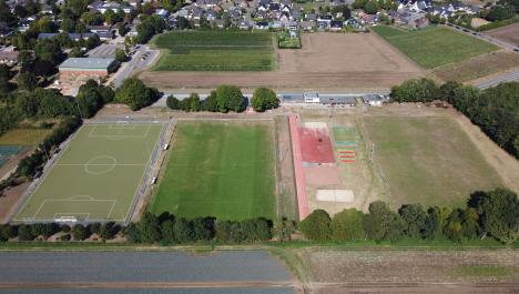 Luftbild Sportanlage Alster Kirchweg Bracht umgeben von Baumbewuchs und Feldern, links Kunstrasenplatz, mittig Rasenplatz, Tartanbahn, Volleyballfeld, Weitsprunganlage, dahinter Vereinsheim, rechts Rasenplatz, im Hintergrund Feld- und Gebäudelandschaft