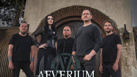 Eine fünfköpfige Band ist komplett in schwarz gekleidet und steht vor einem älteren Mauerwerk. Links steht ein Mann mit schwarzen T-Shirt und eine Frau mit schwarzen Haaren. Mittig und rechts im Bild sind weitere drei Männer zu sehen in schwarzen Oberteilen. Im Vordergrund ist der Schriftzug der Band eingeblendet.