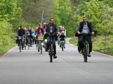 Männliche und Weibliche Radfahrer auf einer Straße umgeben von dichtem Baum- und Strauchbewuchs, im Vordergrund Bürgermeister Frank Gellen und Allgemeiner Vertreter Dieter Dresen